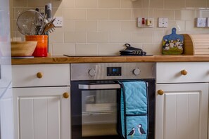 A kitchen with white cabinets, a stainless steel oven, and a wooden countertop. - 2 Bed in Seahouses (oc-s34710) (Seahouses)