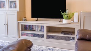 A living room with a flat-screen TV, a bookshelf, a potted plant, and leather sofas. - 2 Bed in Seahouses (oc-s34710) (Seahouses)