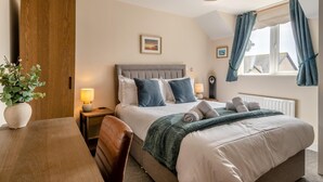 A hotel room with a bed, bedside tables, a desk, and a window with curtains. - 2 Bed in Seahouses (oc-s34710) (Seahouses)