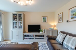 A living room with a flat-screen TV, a bookshelf, a sofa, and a coffee table. - 2 Bed in Seahouses (oc-s34710) (Seahouses)