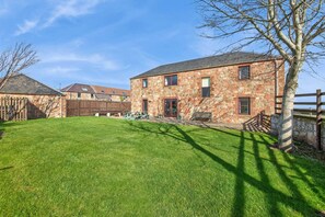 A stone building with a grassy yard, wooden fence, and a bench. - 5 Bed in Cockburnspath (oc-r35051) (Cockburnspath)