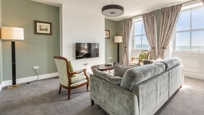 Un salon avec un canapé, un fauteuil, une télévision et une vue sur la mer.