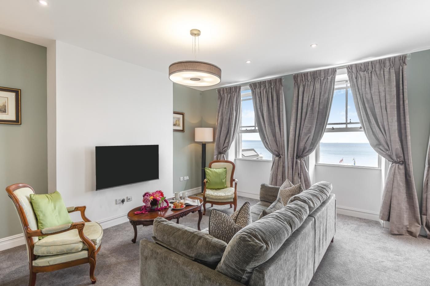 A living room with a sofa, armchairs, a coffee table, and a flat-screen TV.