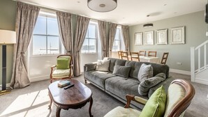 Un salon comprenant un canapé, des fauteuils, une table basse et un coin repas avec des chaises et une table.
