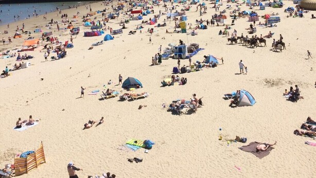 Une plage avec des tentes et des gens qui prennent un bain de soleil.