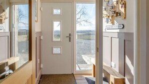 Ein Flur mit einer hölzernen Bank, einer Tür mit satinierten Glasscheiben und einem Schild an der Wand.