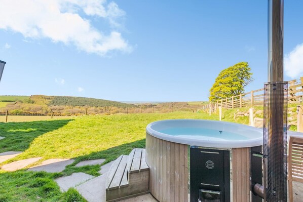 A hot tub in a grassy outdoor area with a view of hills and a tree. - 1 Bed in Ponsonby (oc-l37879) (Ponsonby)