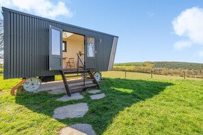 A compact, modern cabin with a small porch, a single chair, and a step leading to the entrance. - 1 Bed in Ponsonby (oc-l37879) (Ponsonby)