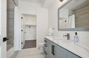 Une salle de bain moderne avec un meuble-lavabo blanc, un grand miroir et un espace douche.