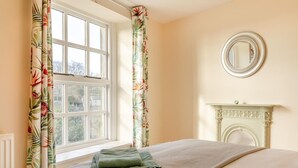 A bedroom with a bed, a window with curtains, a fireplace, and a mirror on the wall. - 3 Bed in Tideswell (oc-w39004) (Tideswell)