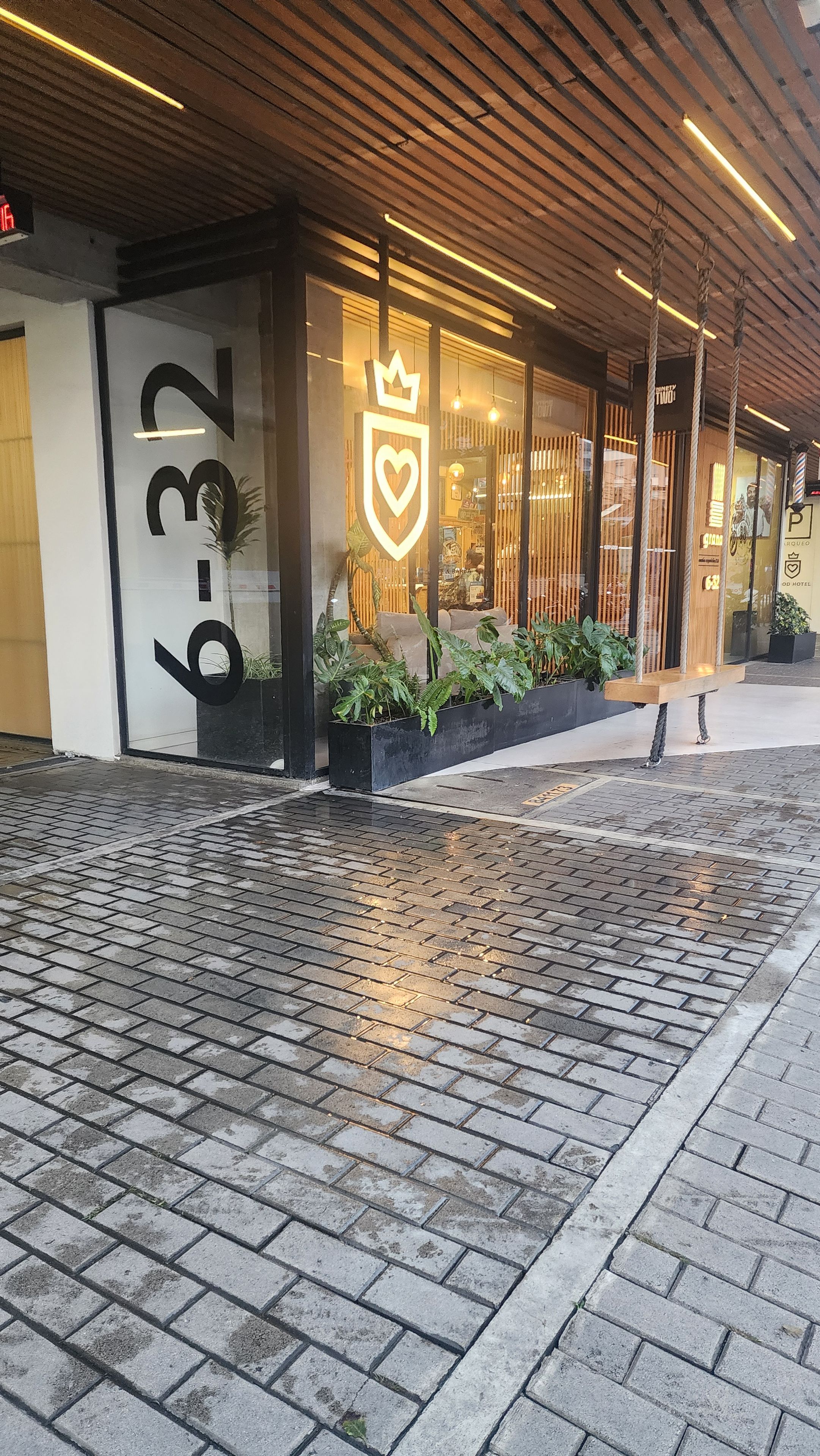 Entrada de un hotel con un número grande, un emblema de corona y plantas en macetas.