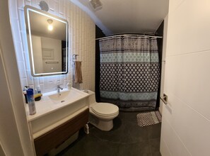 A bathroom with a white sink, a toilet, a mirror, and a shower curtain.