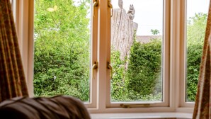 Una ventana con vistas a un árbol y una estatua.