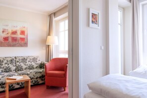 Ein Hotelzimmer mit einer Couch, einem Sessel, einem Nachttisch und einem Bett.