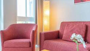A room with a red armchair, a red sofa, a table, and a lamp. - Strandurlaub mit der Familie - Ferienwohnung mit Balkon in Sellin (Sellin)