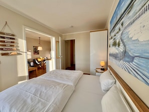 A hotel room with a bed, a desk, a chair, and a painting on the wall. - Seepark Sellin Fewo fur 3 Personen (Sellin)