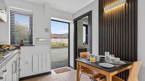 Una cucina moderna con zona pranzo, vista attraverso la porta e un pannello decorativo in legno.