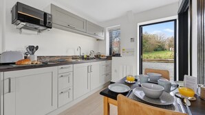 Una cucina moderna con mobili bianchi, un forno a microonde integrato e un'area pranzo con tavolo imbandito per due persone.