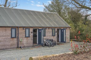 Ein Holzhaus mit Metalldach, ein Fahrrad vor der Tür und ein Schotterweg.