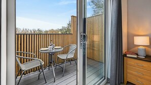 A balcony with a table and chairs, a sliding glass door, and a bedside table with a lamp. - 1 Bed in Minsterley (oc-s38642) (Minsterley)