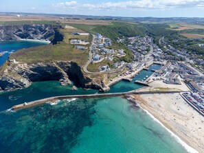 Luftaufnahme einer Küstenstadt mit einem Yachthafen, Sandstrand und Wohnhäusern.