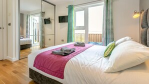 Un dormitorio con cama, televisión, balcón y puerta corredera.