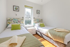 Ein Schlafzimmer mit zwei Betten, einem Fenster und einem Nachttisch.