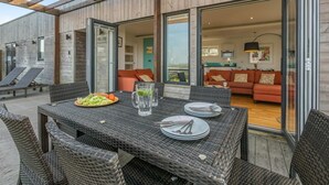 Un espacio para comer al aire libre con mobiliario de mimbre, una mesa preparada para cuatro personas y vista al salón.