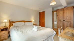 Un dormitorio con una cama, lámparas de noche, un armario de madera y un espejo.