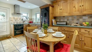 Una cocina con armarios de madera, una mesa de comedor para cuatro personas y un horno empotrado.