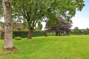 A well-maintained grassy lawn with mature trees and a wooden fence.