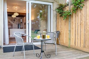 A patio with two wicker chairs, a small round table with a coffee pot and glasses, and a wooden fence with climbing plants. - 2 Bed in Battle (oc-sx913) (Battle)