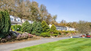 A residential street with houses, a well-maintained lawn, and parked cars. - 2 Bed in Notter (oc-k39063) (Notter)