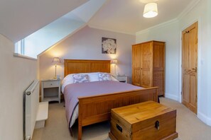 A bedroom with a wooden bed, nightstands, a wooden wardrobe, a chest of drawers, and a window. - 2 Bed in Reydon (oc-s39034) (Reydon)