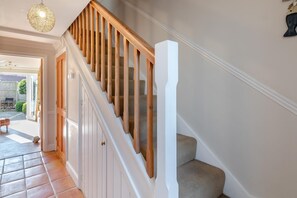 A staircase with wooden railings and white walls, leading to an outdoor area with a patio and a view of a garden. - 2 Bed in Reydon (oc-s39034) (Reydon)