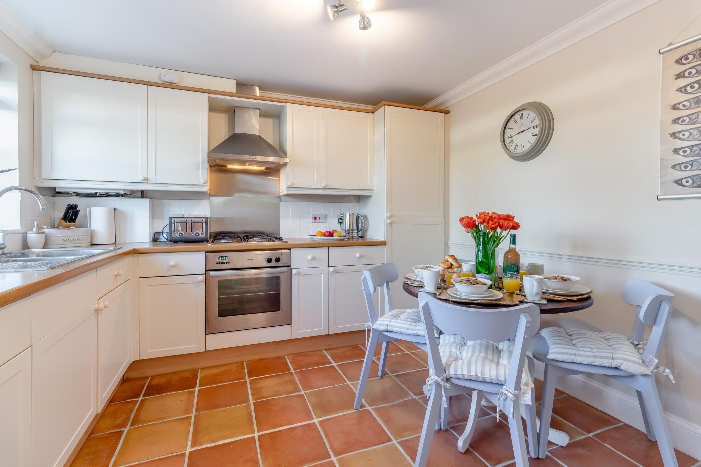 A compact kitchen with white cabinets, a stove, oven, and a dining area with a table set for breakfast.