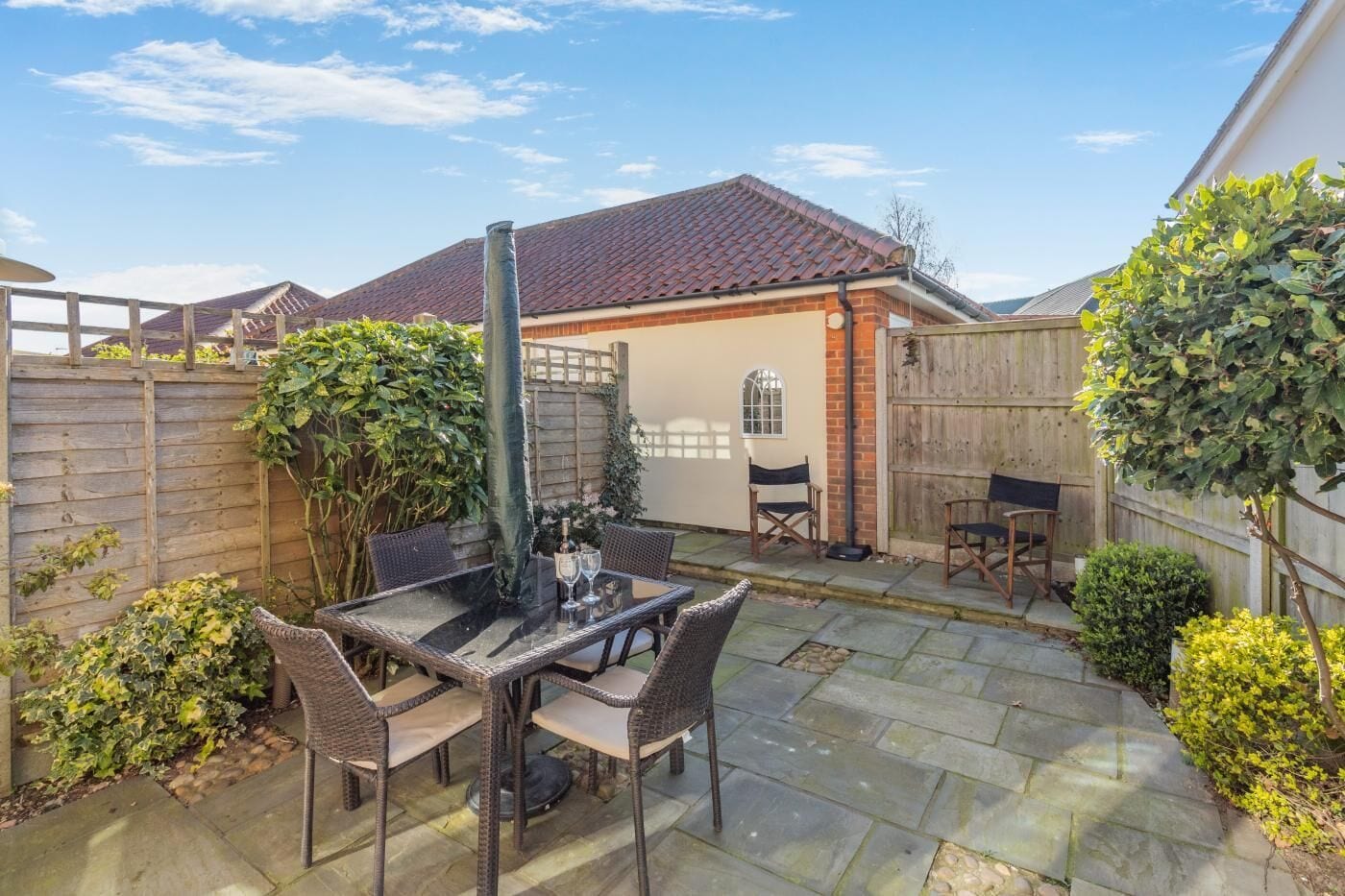 A patio with a table and chairs, a brick wall, and a wooden fence.