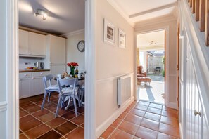 A kitchen with white cabinets, a dining table with chairs, a clock, and a radiator. - 2 Bed in Reydon (oc-s39034) (Reydon)