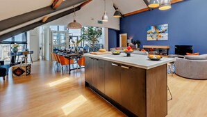 A modern kitchen with a central island, wooden beams, pendant lighting, and a view to the outside. - 2 Bed in Borth (oc-ystiw4) (Glanwern)