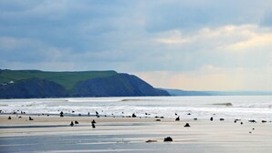 A beach with a distant view of green hills and a cloudy sky. - 2 Bed in Borth (oc-ystiw4) (Glanwern)