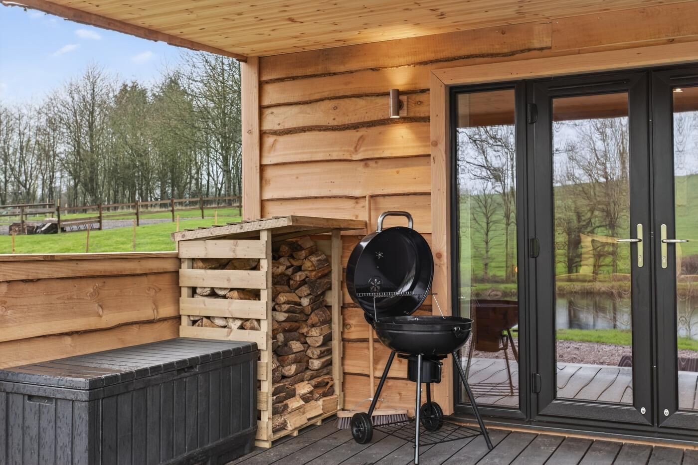 Une cabane en bois avec un barbecue et un mur en pierre.