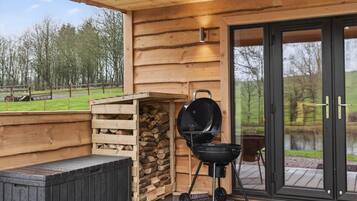 Une cabane en bois avec un barbecue et un mur en pierre.
