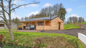 Eine Blockhütte mit Veranda, Grill und Blick auf ein Gewässer.