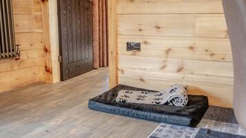 Un intérieur en bois avec un panier pour animaux de compagnie, un radiateur et une porte.