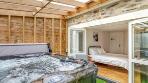 Un jacuzzi en una habitación con cama y pared de piedra.