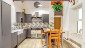 Una cocina moderna con armarios grises, una mesa de comedor de madera y una planta colgante.