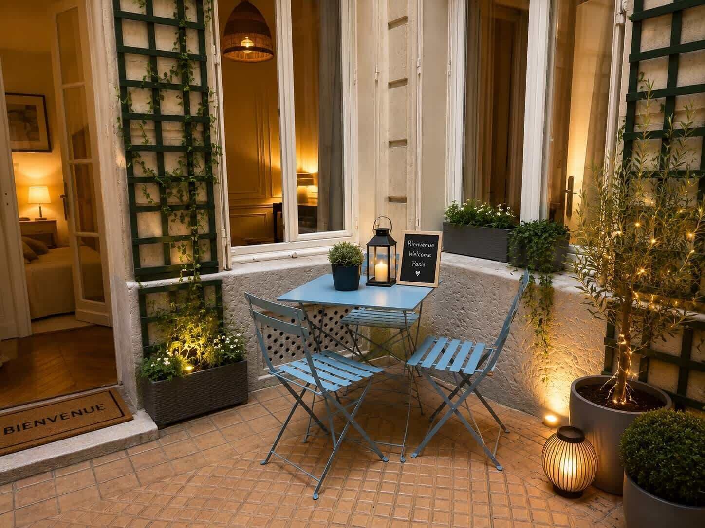 A patio with a table and chairs, a welcome sign, and potted plants.