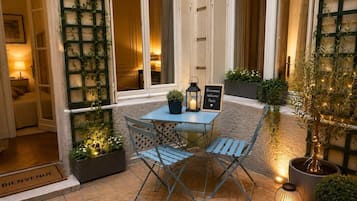A patio with a table and chairs, a welcome sign, and potted plants.
