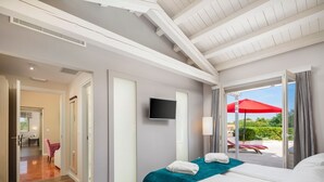 A hotel room with a bed, a TV, a window with a view of the outdoors, and a door leading to a bathroom. - Casa Andrik - Five Bedroom Villa, Sleeps 12 (Režanci)
