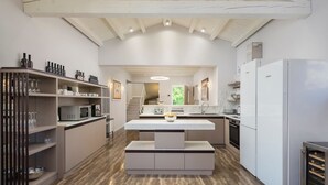 A modern kitchen with white cabinetry, a central island, and a wooden ceiling. - Casa Andrik - Five Bedroom Villa, Sleeps 12 (Režanci)